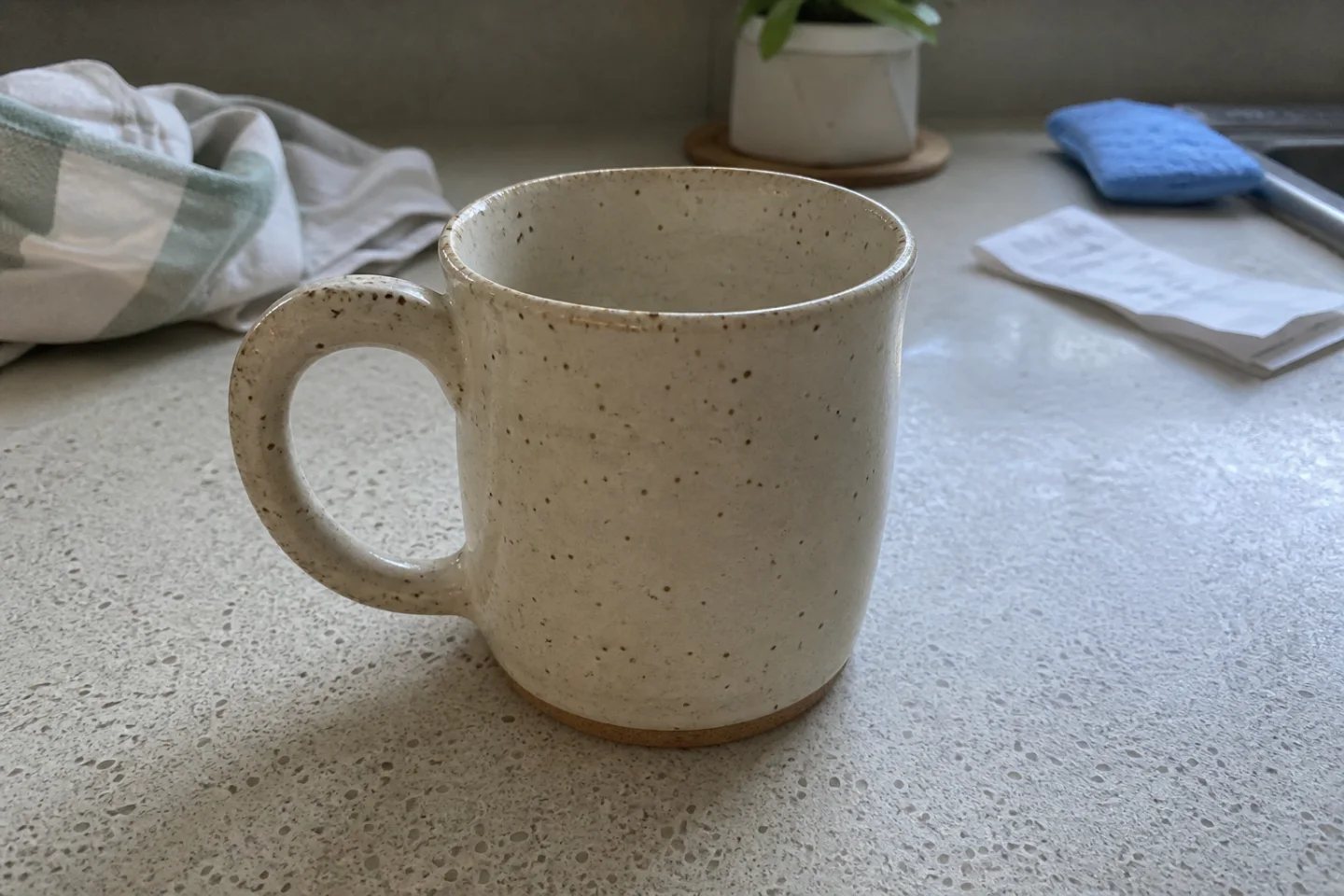 Ordinary handmade ceramic mug photo on a cluttered kitchen counter