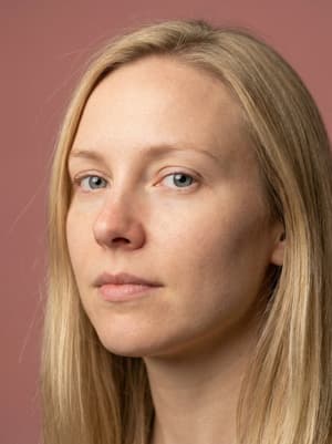 Ultra-photorealistic shoulder-cropped portrait of Nordic woman with highly detailed skin texture, visible pores, light freckles, grey-blue eyes, blonde hair, dusty rose backdrop
