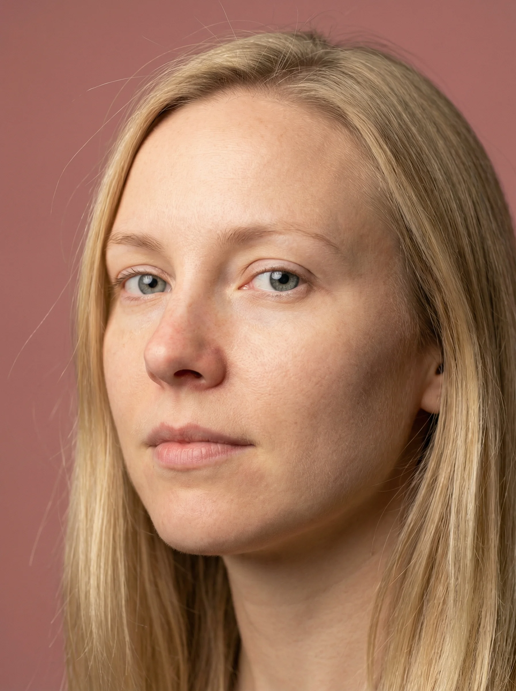 Ultra-photorealistic shoulder-cropped portrait of Nordic woman with highly detailed skin texture, visible pores, light freckles, grey-blue eyes, blonde hair, dusty rose backdrop