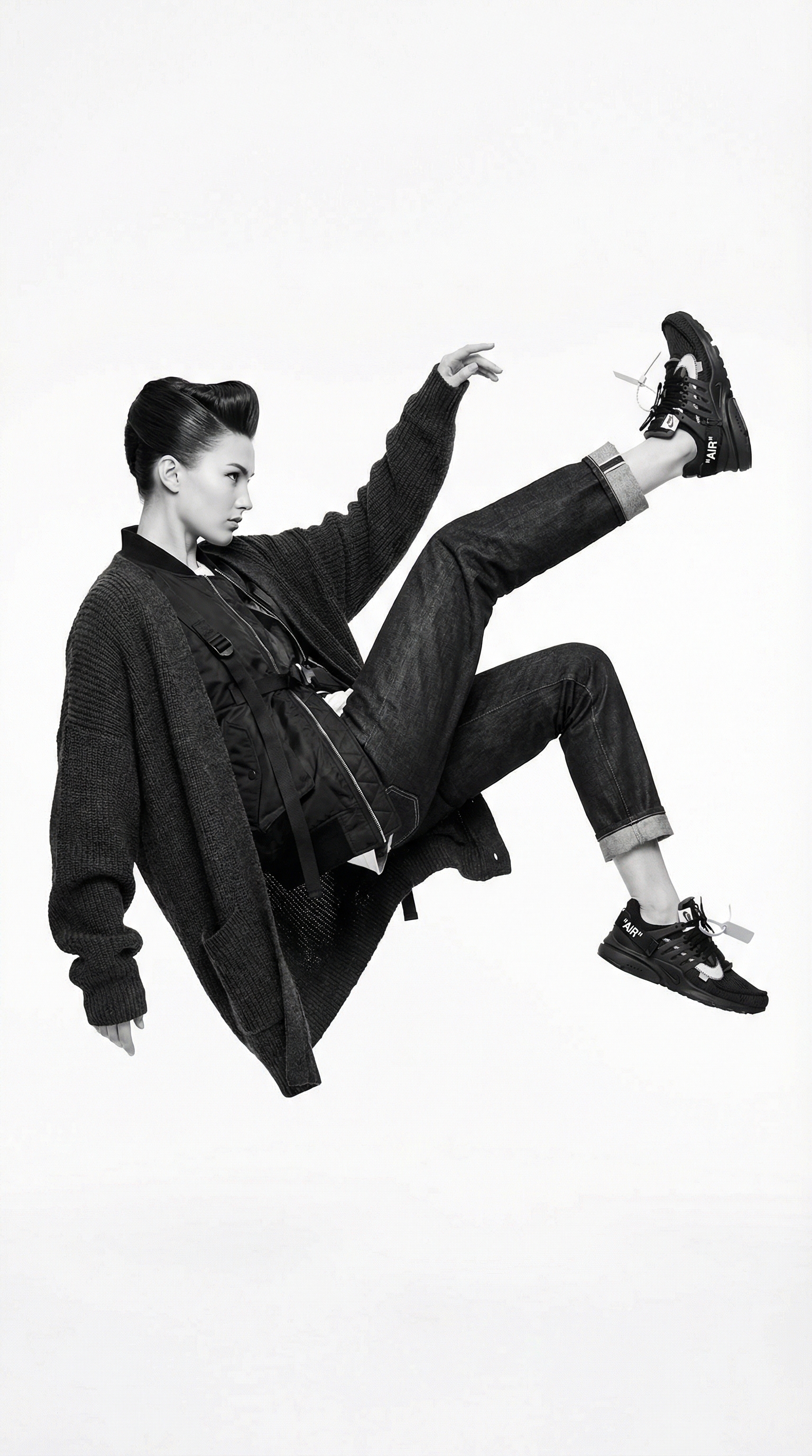 Cinematic luxury hypebeast editorial in strictly monochrome with shadowless stasis and deep rich blacks, featuring woman in impossible gravity-defying airborne pose with creative street fashion by brands like Supreme Fear of God Maison Margiela, wearing premium sneakers against pure white infinite void background with no shadows